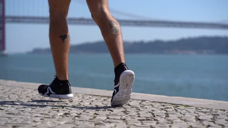 Legs-of-tattooed-sportsman-running-at-riverside